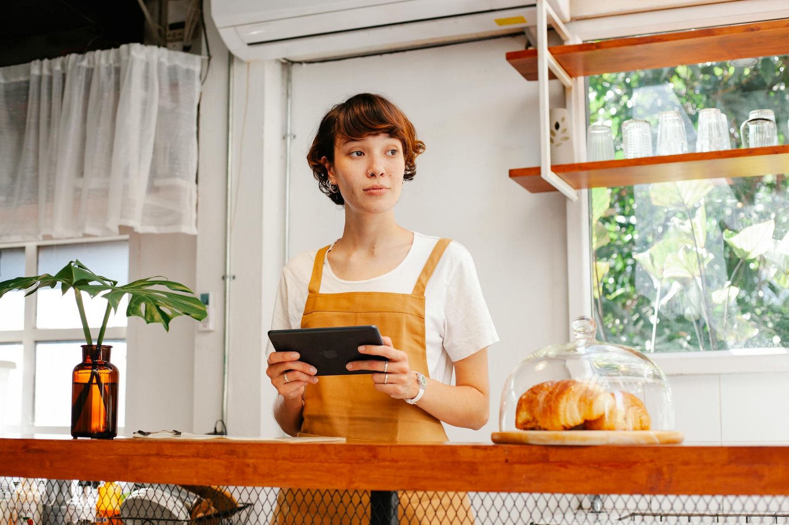 A baker interacting with a tablet displaying Google My Business insights for their artisanal bakery, showing positive reviews and local search performance.